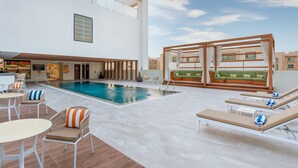 A rooftop pool area with lounge chairs, a small table, and a seating area with a green sofa. - Holiday Inn & Suites Al Jubail by IHG (Al Jubail)