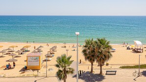 Ein Strand mit Sonnenschirmen, Liegestühlen und einem Schild mit der Aufschrift 'Praia Alegre'.