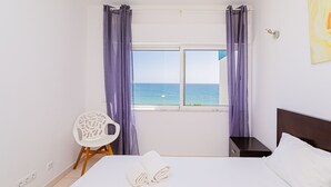 Ein Hotelzimmer mit Bett, Nachttisch, Stuhl und einem Fenster mit Vorhängen.