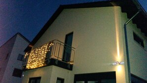 Ein Gebäude mit einem Balkon, der mit Lichterketten geschmückt ist, einem Fenster und einer Tür.