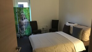 Ein Hotelzimmer mit einem großen Bett, zwei Sesseln, einem kleinen Tisch und einer Buddha-Statue an der Wand.