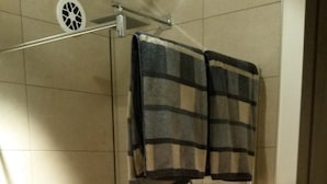 Eine Duschkabine mit Glaswänden, einer Handbrause und einem Handtuchhalter darüber.