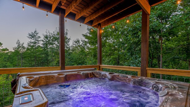 A hot tub with a wooden deck and a view of trees. - Free Tickets | Private Balcony, Grill, Game Room, Hot Tub, Great Location (Sevierville)