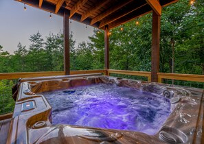 Ein Whirlpool mit einer Holzterrasse und Blick auf Bäume.