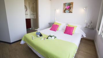 A hotel room with a bed, a bathroom visible through an open door, and a wall-mounted artwork.