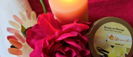Et lys, en beholder med massageolie og en blomstbuket.