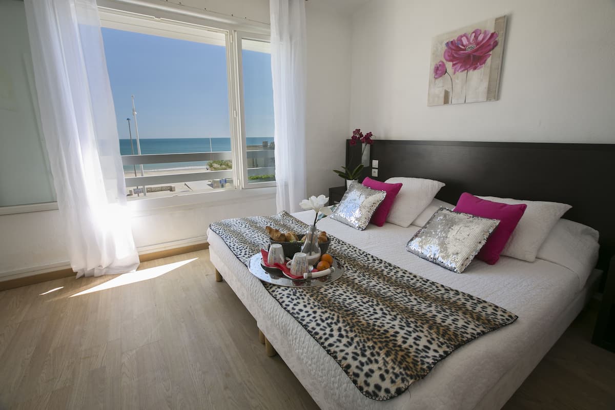 Ein Schlafzimmer mit einem großen Bett, Meerblick vom Balkon und einem Gemälde an der Wand.