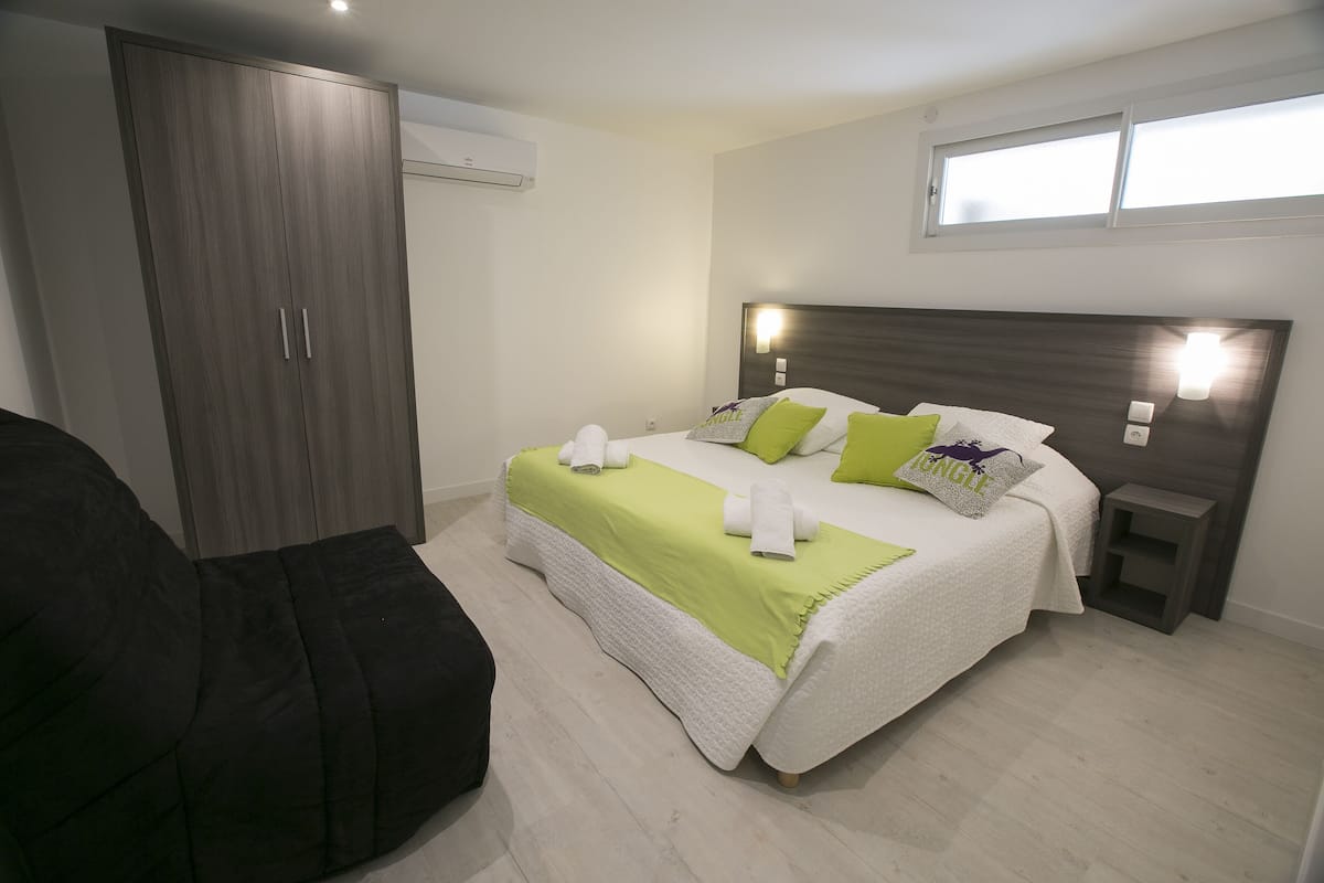 Ein Schlafzimmer mit einem Bett, einem Kleiderschrank, einem Nachttisch und einem Fenster.