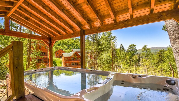 A wooden deck with a hot tub overlooking a forested landscape.