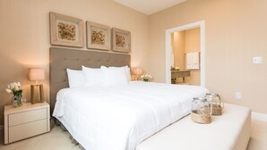 Une chambre à coucher bien aménagée, avec un grand lit, des tables de chevet avec des lampes et des œuvres d’art décoratives au mur.