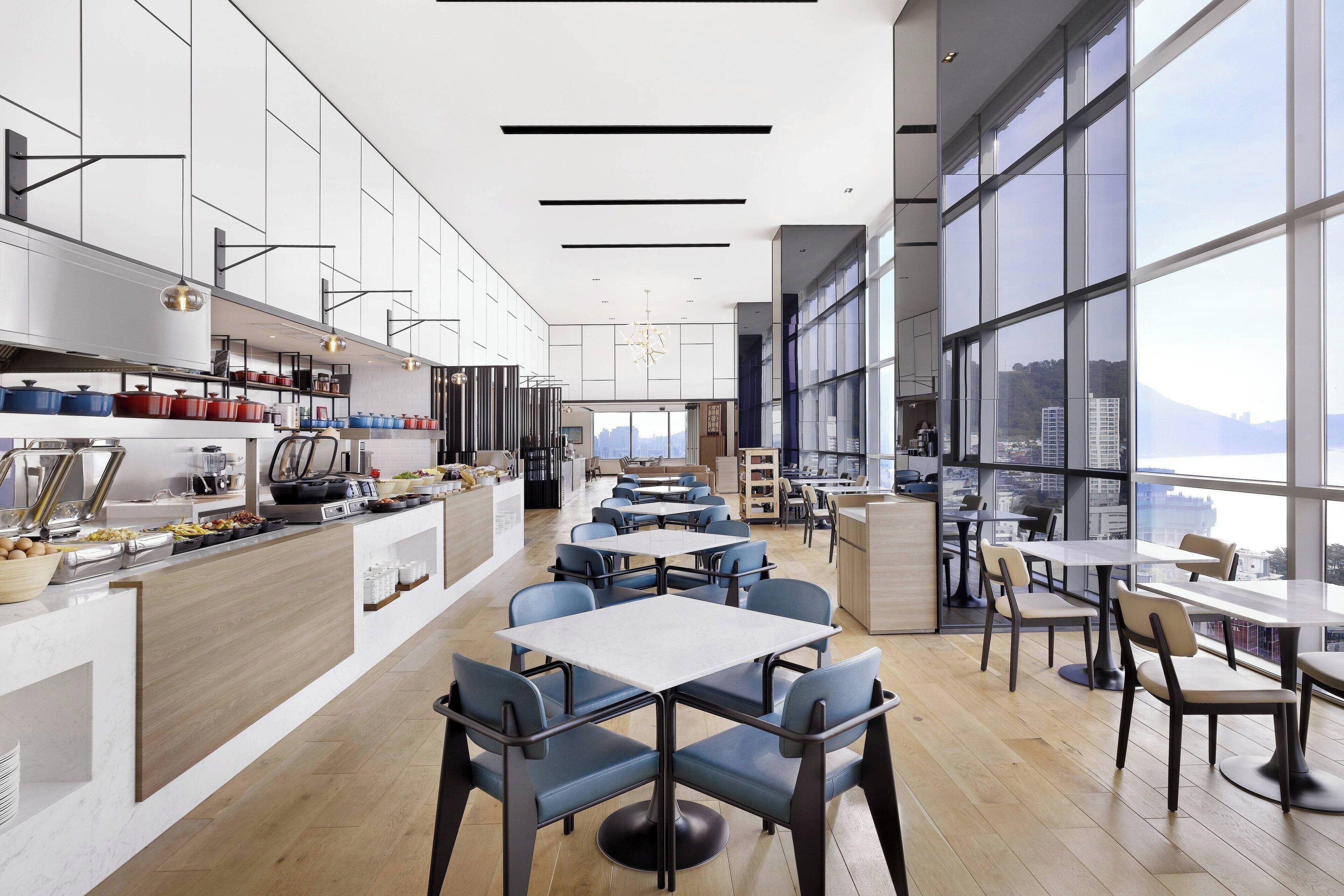 Un restaurante moderno con una barra larga, varias mesas y sillas.