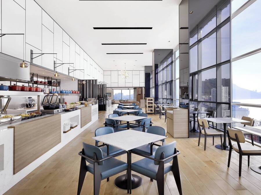 Un restaurante moderno con una barra larga, varias mesas y sillas.