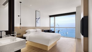 A modern hotel room with a large bed, a bathroom with a marble sink, and a view of the sea. - Fairfield by Marriott Busan Songdo Beach (Busan)