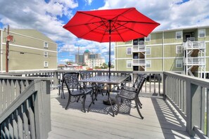 Enjoy a refreshing drink on the balcony with a metal table and chairs, shaded by a parasol.