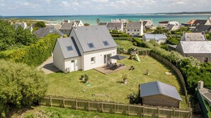 A residential area with houses, a grassy yard, and a view of the sea.