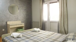 A bedroom with a bed, a bedside table, a mirror, and a window with curtains. - GARDEN APARTMENT with 3 bedrooms (Budva)