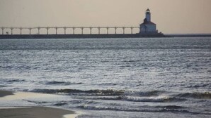 Un faro junto al mar con un muelle que se adentra en el agua.