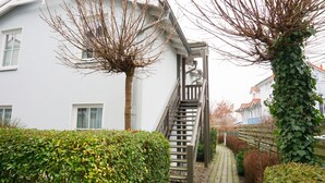 Una casa blanca con una escalera de madera que lleva a un balcón.