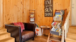 A cozy room with a leather chair, a bookshelf, and a sign saying "I'M Walkin' on SUN SHINE". - Red Fox Hollow - Hocking Hills, Clear Creek, Hot Tub, Fire Pit and Swing (AMANDA)
