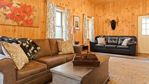 A wooden-paneled room with two leather sofas, a wooden coffee table, and a mounted deer head. - Red Fox Hollow - Hocking Hills, Clear Creek, Hot Tub, Fire Pit and Swing (AMANDA)
