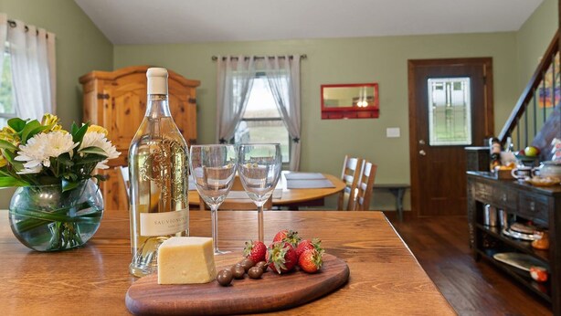 A dining table with a bottle of wine, glasses, cheese, and strawberries. - Red Fox Hollow - Hocking Hills, Clear Creek, Hot Tub, Fire Pit and Swing (AMANDA)