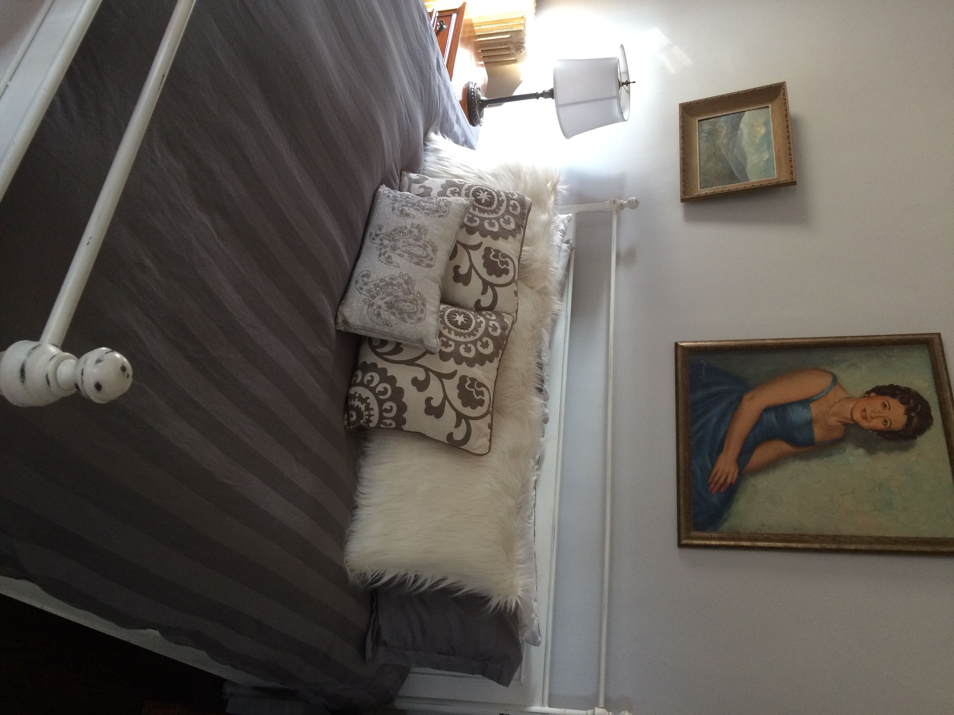 Une chambre à coucher avec un lit, des oreillers, un tableau et une lampe.