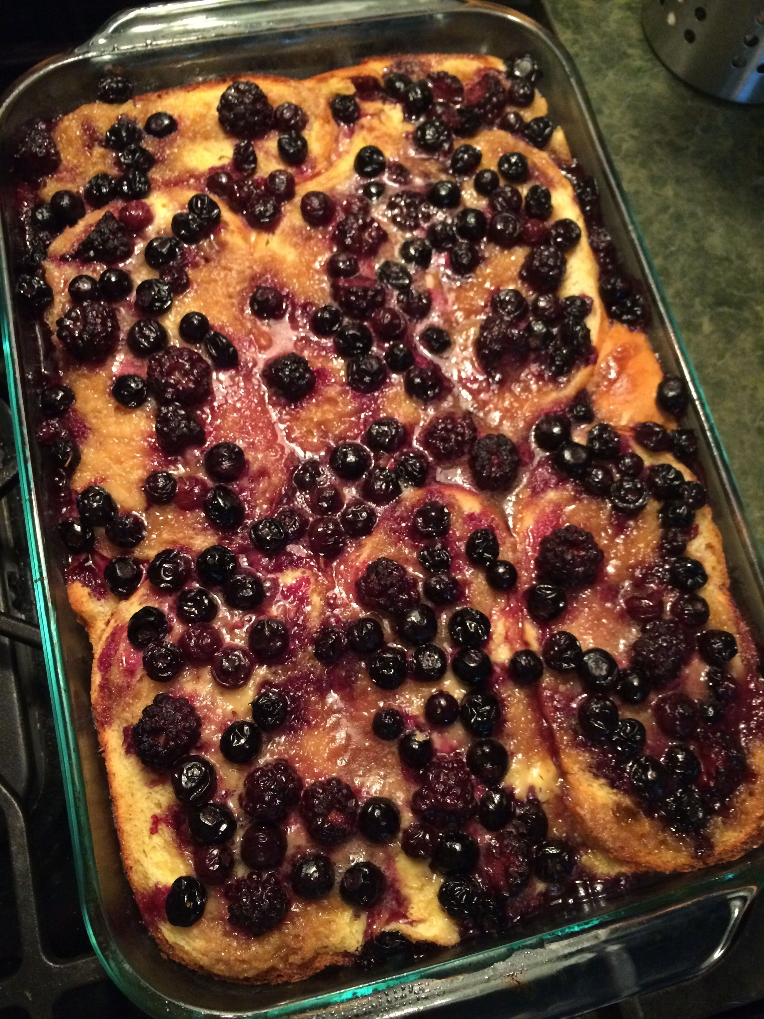 A glass baking dish with a baked dessert topped with berries.