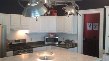 A kitchen with a central island, stainless steel appliances, and white cabinetry.
