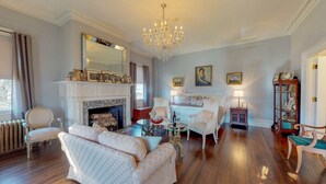 A spacious living room with a fireplace, elegant furniture, and a chandelier. - Gardner Farm Inn (Troy)