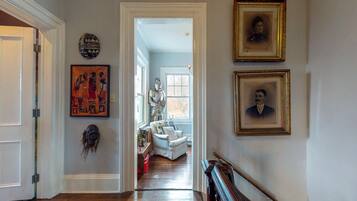A hallway with a white door, a framed portrait, and a statue.