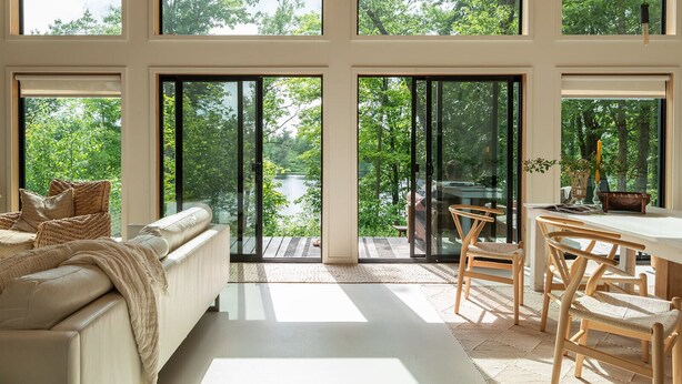 Una habitación amplia con ventanas grandes, un sofá, una mesa de comedor y sillas.
