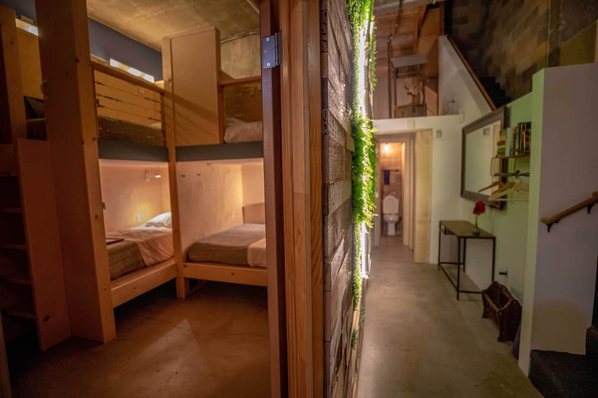 Une pièce chaleureuse et spacieuse, aménagée sur plusieurs niveaux, avec des lits superposés et un escalier.