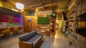 Un rincón de sala acogedor con sofá, sillones, una mesita de centro y un televisor montado en la pared.