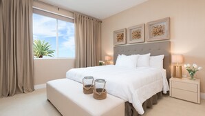 A bedroom with a large bed, a bedside table with a lamp, and a window with curtains.