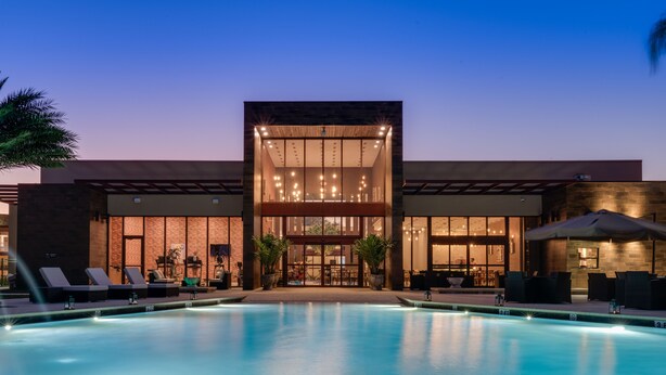 A modern building with a swimming pool, lounge chairs, and outdoor seating.