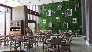 A restaurant with a green wall, wooden furniture, and hanging lights.