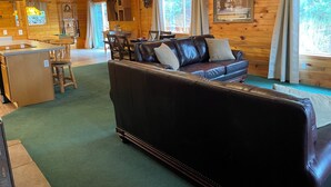 A cabin interior with a wooden interior, a leather sofa, a dining area, and a kitchen. - Bryce & Zion midpoint!  Firepit & pool table. ATV trails nearby. (Alton)