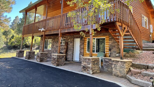 A log cabin with a wooden deck, stone pillars, and a staircase leading to a second level. - Bryce & Zion midpoint!  Firepit & pool table. ATV trails nearby. (Alton)