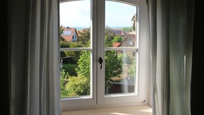 Une pièce dotée d’une grande fenêtre offrant une vue sur des maisons et de la verdure.