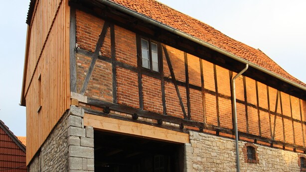 Un bâtiment historique doté d’une vaste entrée ouverte, de murs en pierre et d’un toit recouvert de tuiles.