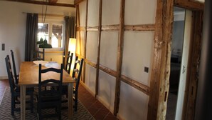 Un coin repas avec une table et des chaises en bois, une lampe et une vue sur une fenêtre avec des rideaux.