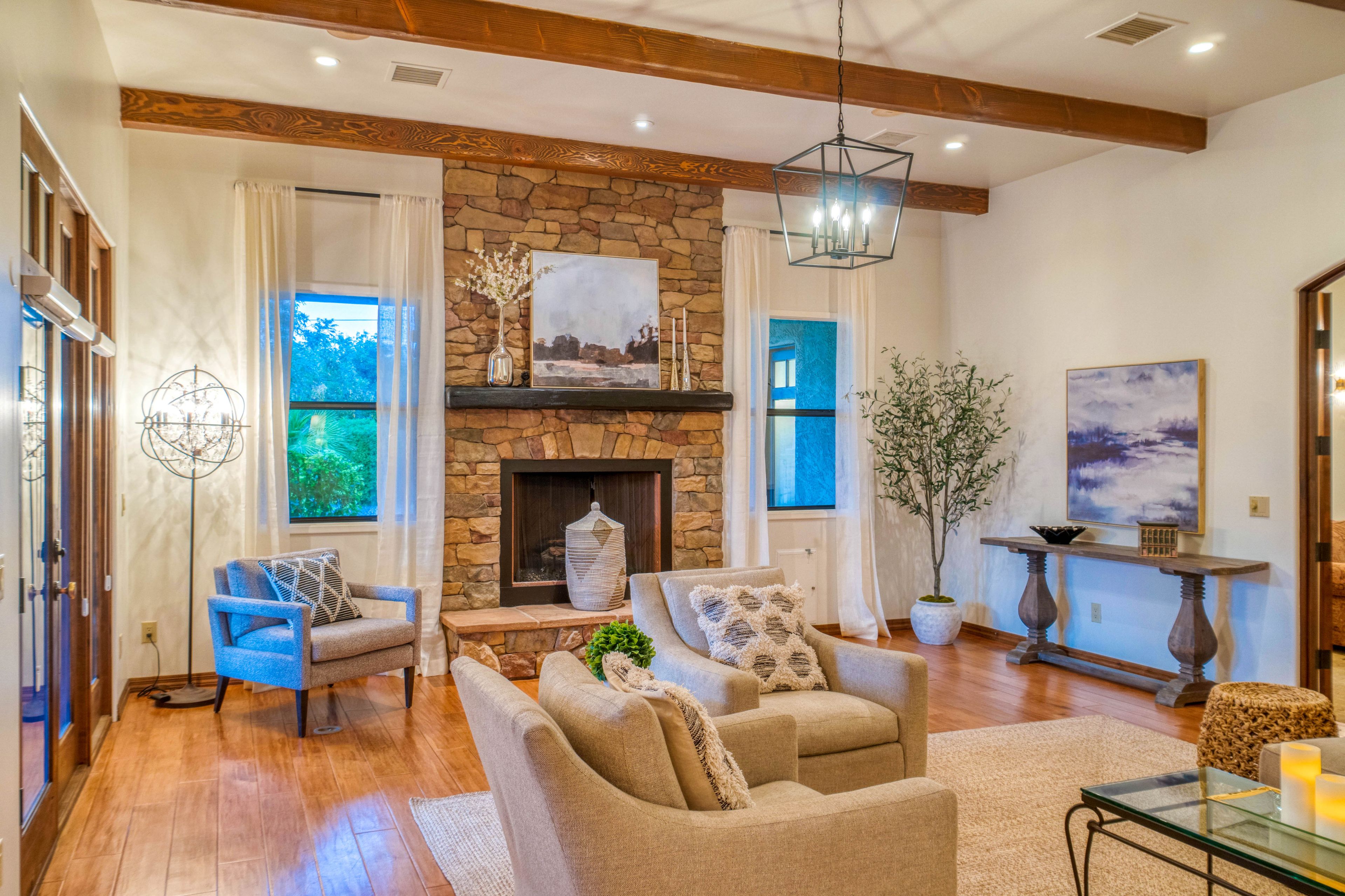 A spacious living room with a stone fireplace, comfortable seating, and large windows.