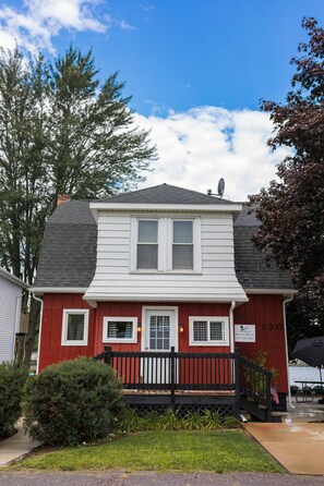 A two-story house with a red exterior, white trim, and a black front porch.