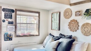 A bedroom with a bed, a window, wall decorations, and a ceiling light. - Private & Cozy cabin with Hot Tub-Coffee Bar-Cowboy Pool (Hot Springs)