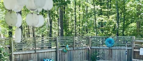A backyard with a wooden deck, two lounge chairs, a hot tub, and a small pond.