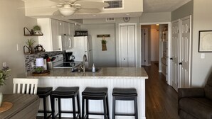 A kitchen with a central island, bar stools, a ceiling fan, and a refrigerator.