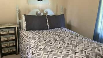 A bedroom with a bed, a nightstand, a wall-mounted artwork, and a ceiling fan.