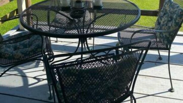 Une terrasse couverte avec une table ronde et des chaises, donnant sur un lac avec un quai et une jetée.