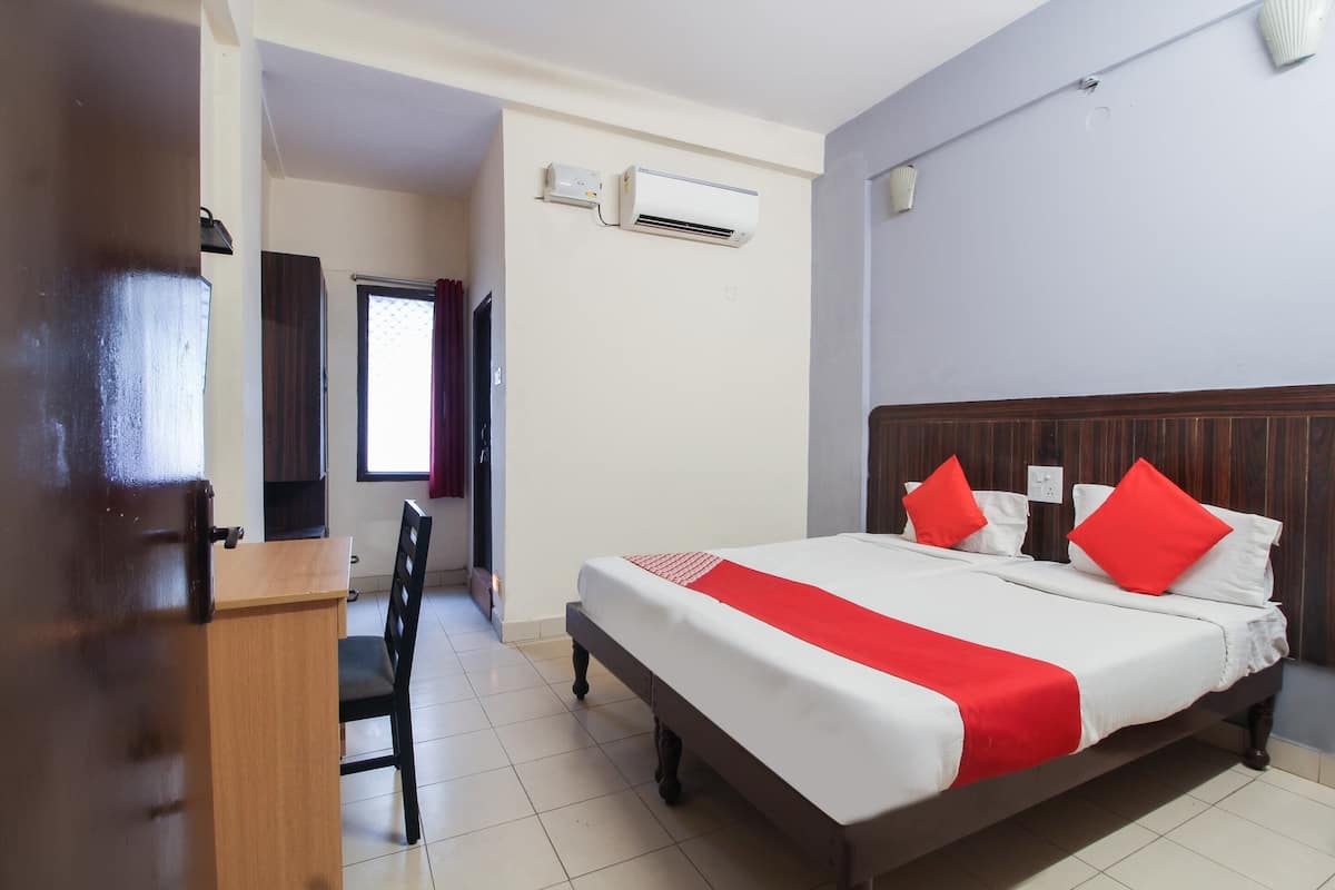 Een hotelkamer met een bed, een bureau en een airconditioner.