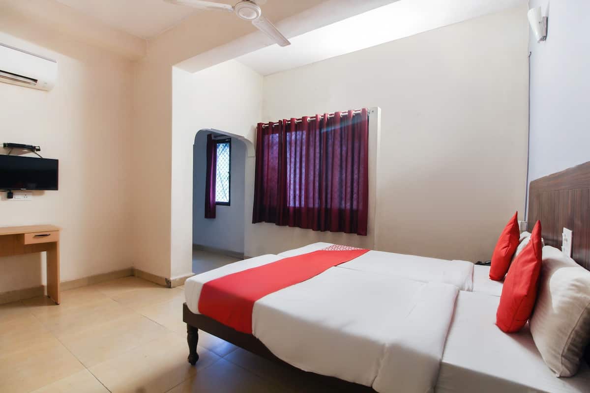 Een hotelkamer met een bed, een bureau, een televisie en een raam met gordijnen.